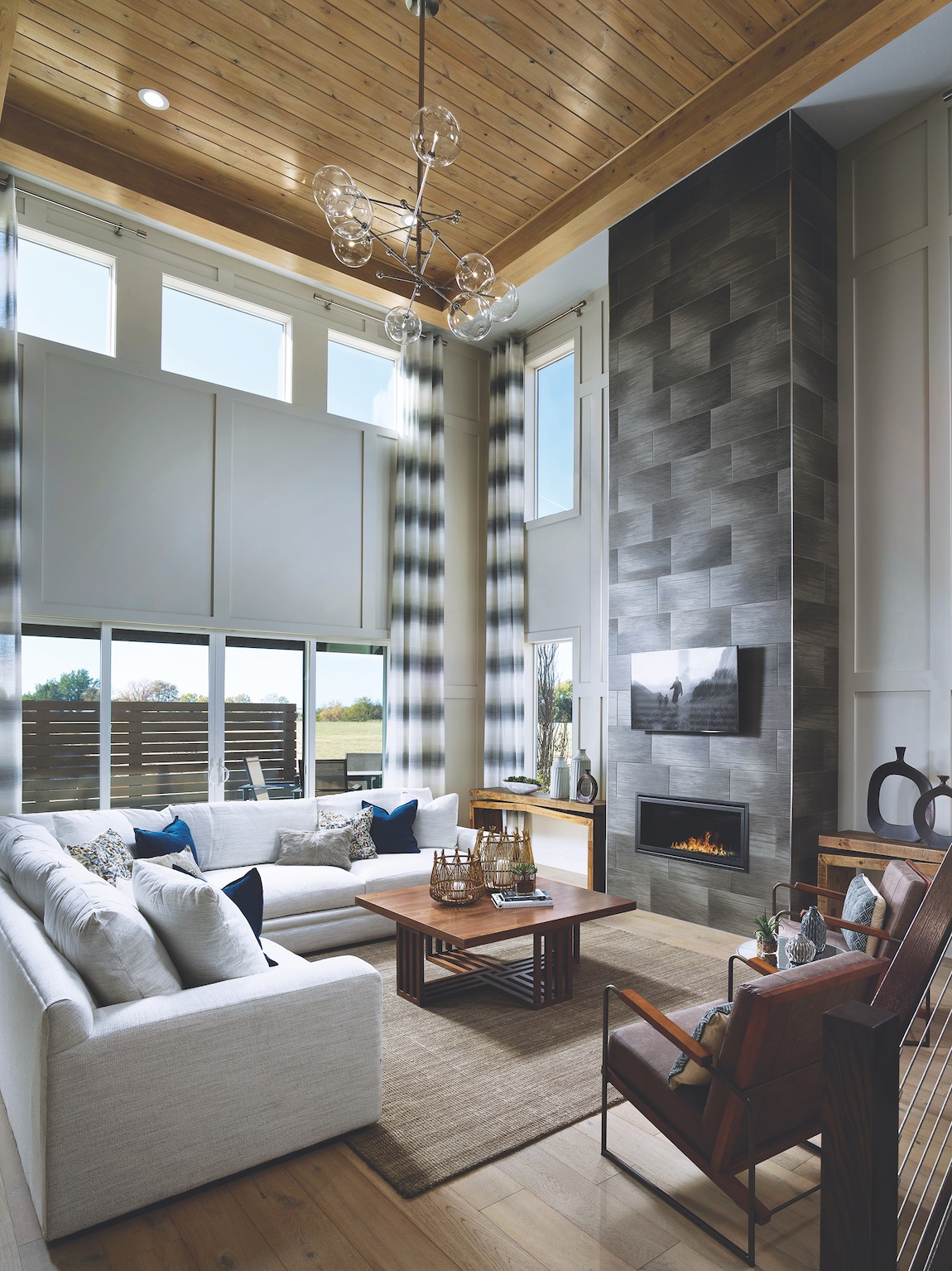 Great room with floor to ceiling windows, white couch, and electric fireplace