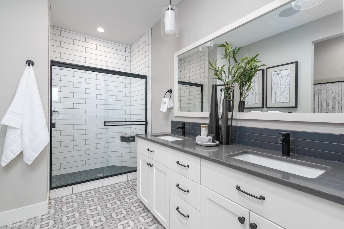 bathroom with dual sinks and patterned floor tiles