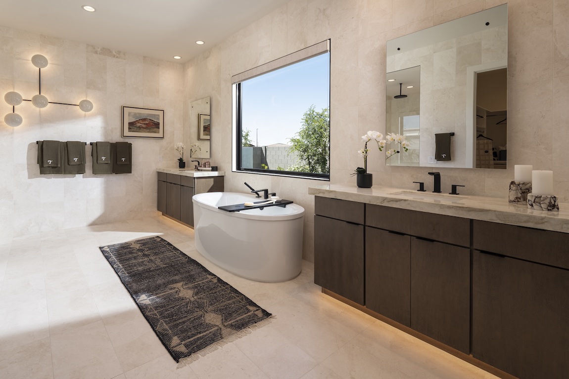 primary bathroom with dual vanities and freestanding tub in the center