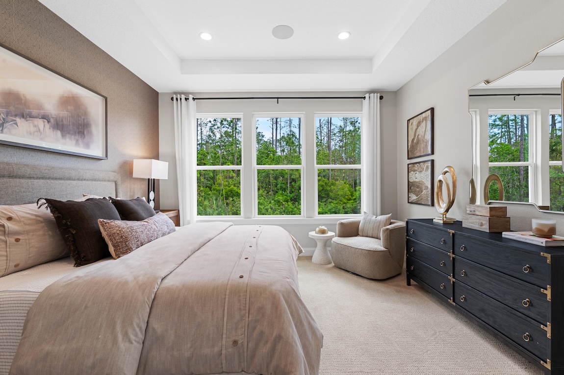 Secondary bedroom with taupe wells, dark wood nightstand, and books 