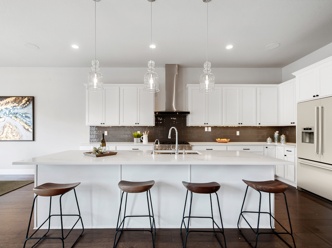 A modern kitchen with white cabinets, countertops and a while center island. 