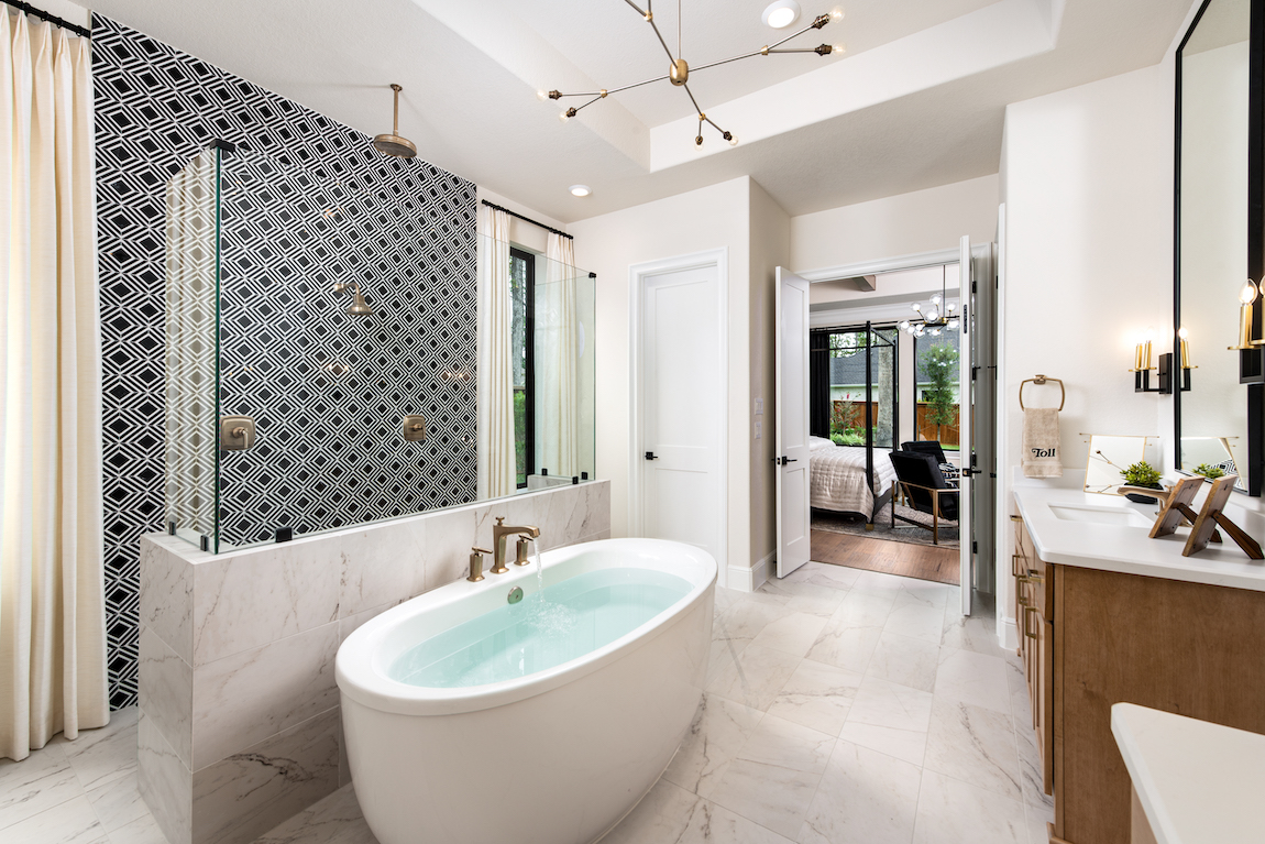 A luxury bathroom with a free-standing bathtub, an accent wall and gold fixtures.