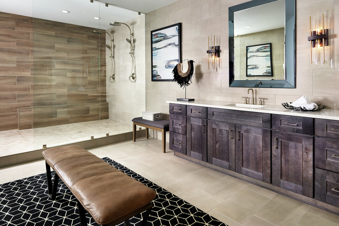 Large primary bathroom with an accent wall in a walk-in shower and brown cabinets.