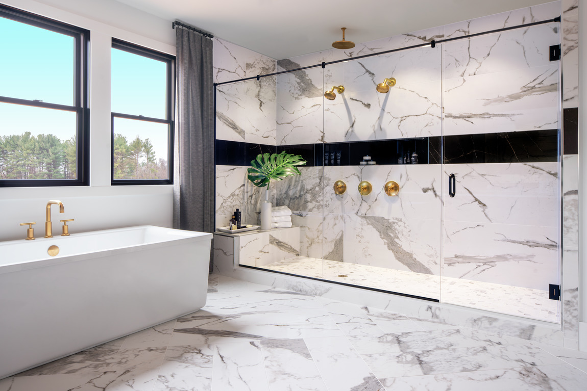 Primary bathroom with a freestanding bathtub and a large shower with gold faucets.