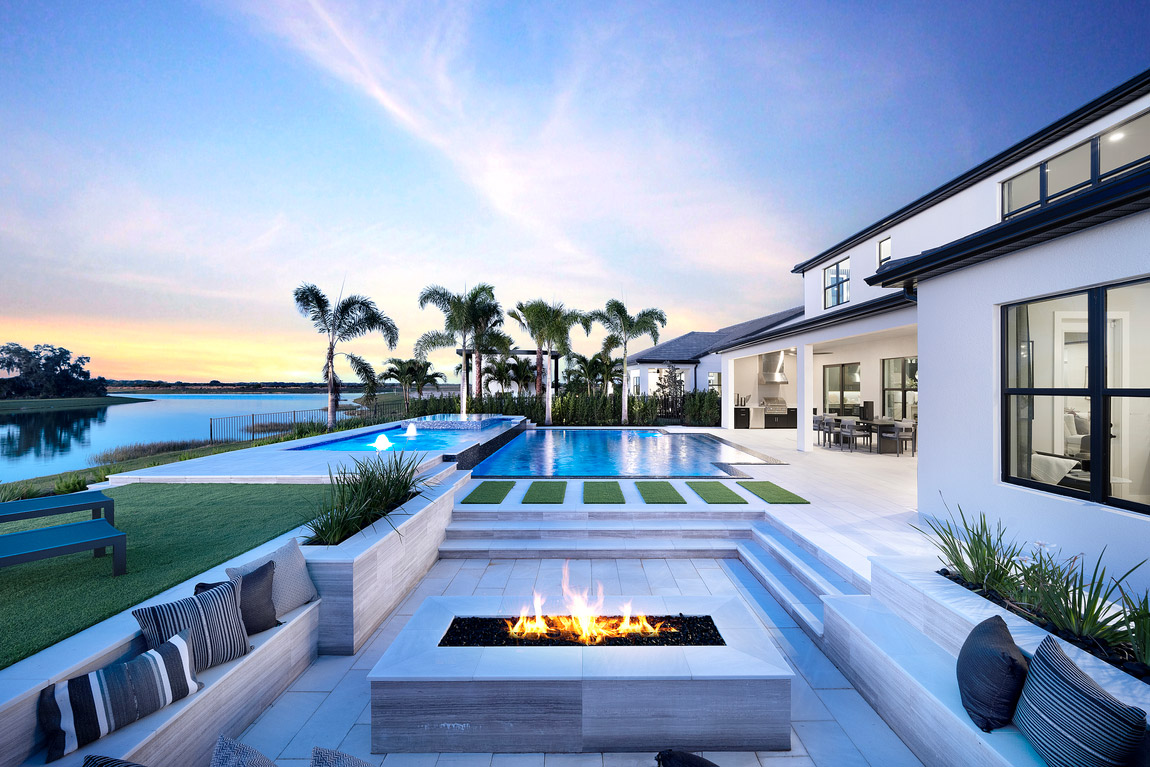 Luxury outdoor living backyard with built-in fireplace, pool, and dining table in Flordia. 