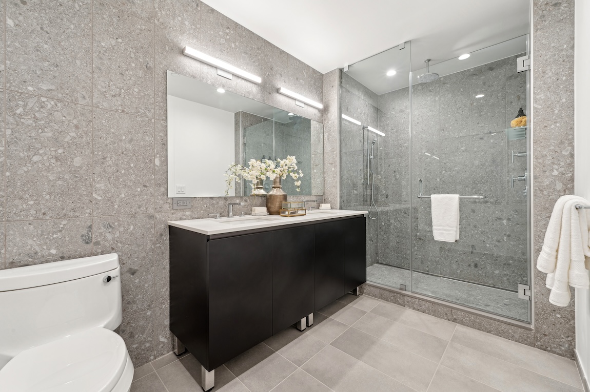 Bathroom design with clear walk-in shower and sleek modern black and white vanity. 