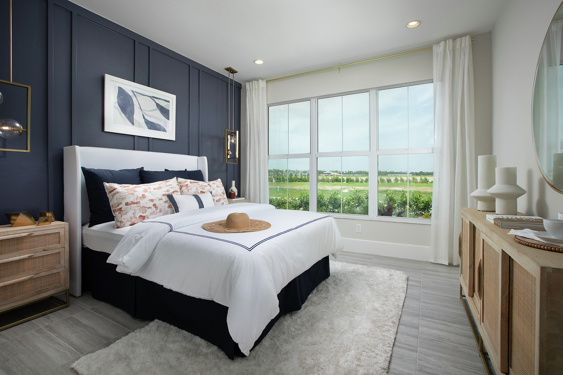 Bedroom highlighted by large windows and dark blue accent wall