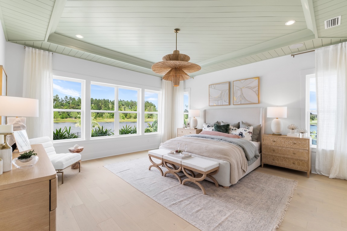 light, airy primary bedroom featuring recessed accent ceiling