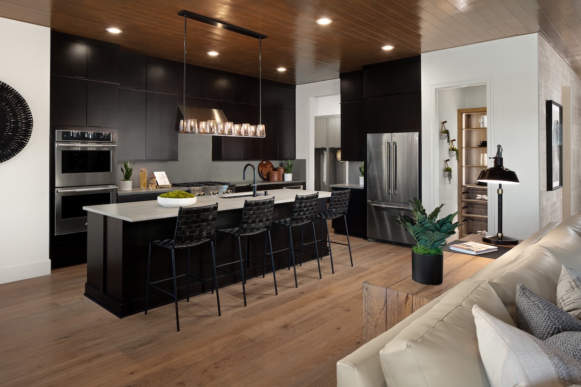 high-contrast kitchen design featuring matte black cabinets, island, and seating paired with warm wood flooring