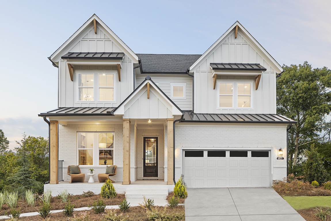 Exterior of luxury home by Toll Brothers with white stone, wooden pillars and board and batton siding in Cumming, Georgia. 