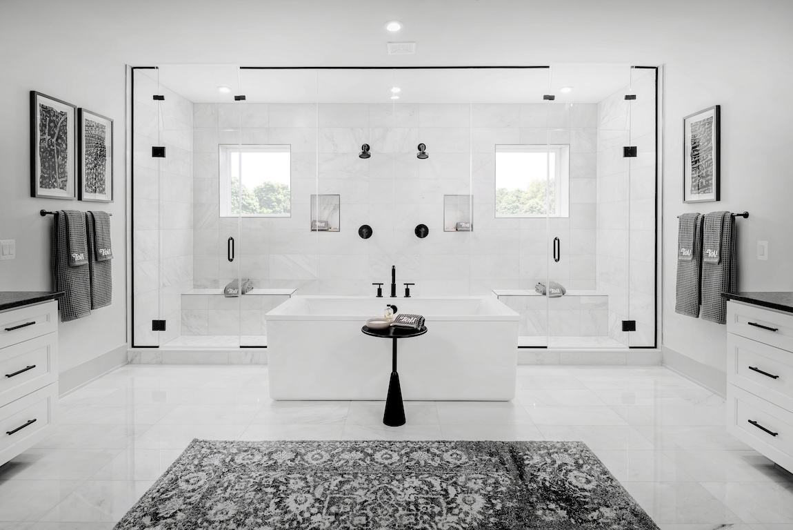 luxe primary bathroom with dual walk-in shower design and central freestanding bathtub