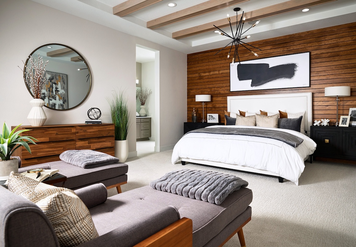 Luxury bedroom by Toll Brothers featuring wooden furrniture accents, carpet flooring, wood beam ceiling and contemporary design in Parker, Colorado. 