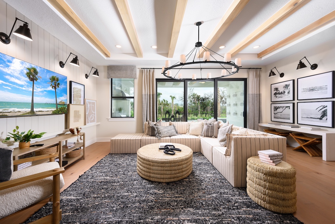 Luxury living room with wood beam ceilings, matte black light fixtures and L-shaped couch in Vero Beach, Florida. 