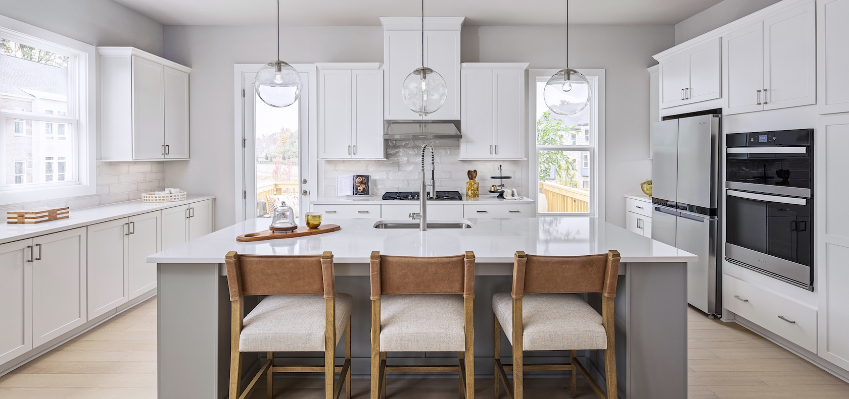 Luxury kitchen design featuring white kitchen cabinets and wooded island chars with waterfall countertop