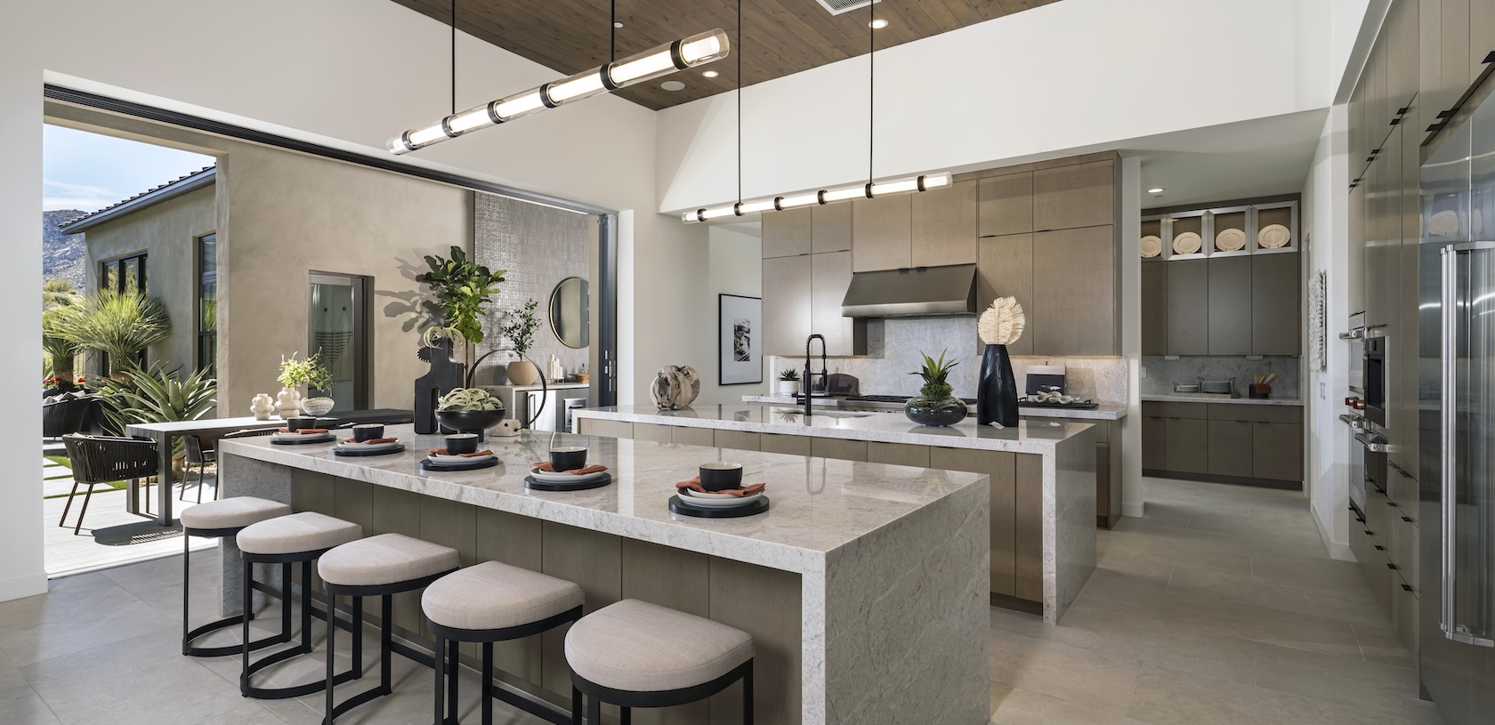 Luxury kitchen with waterfall island, circular stools and indoor to outdoor living space.