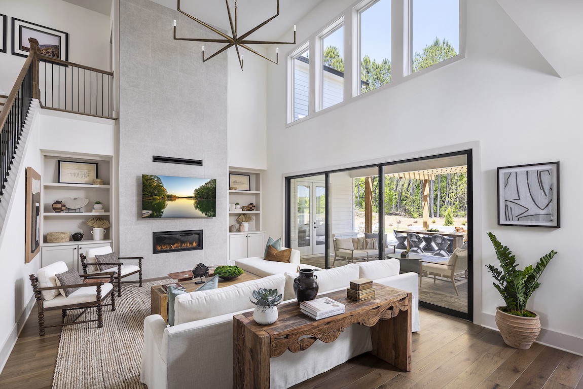 Double-story living room with wooden floors, white walls, and expansive sliding doors in luxury Toll Brothers community. 