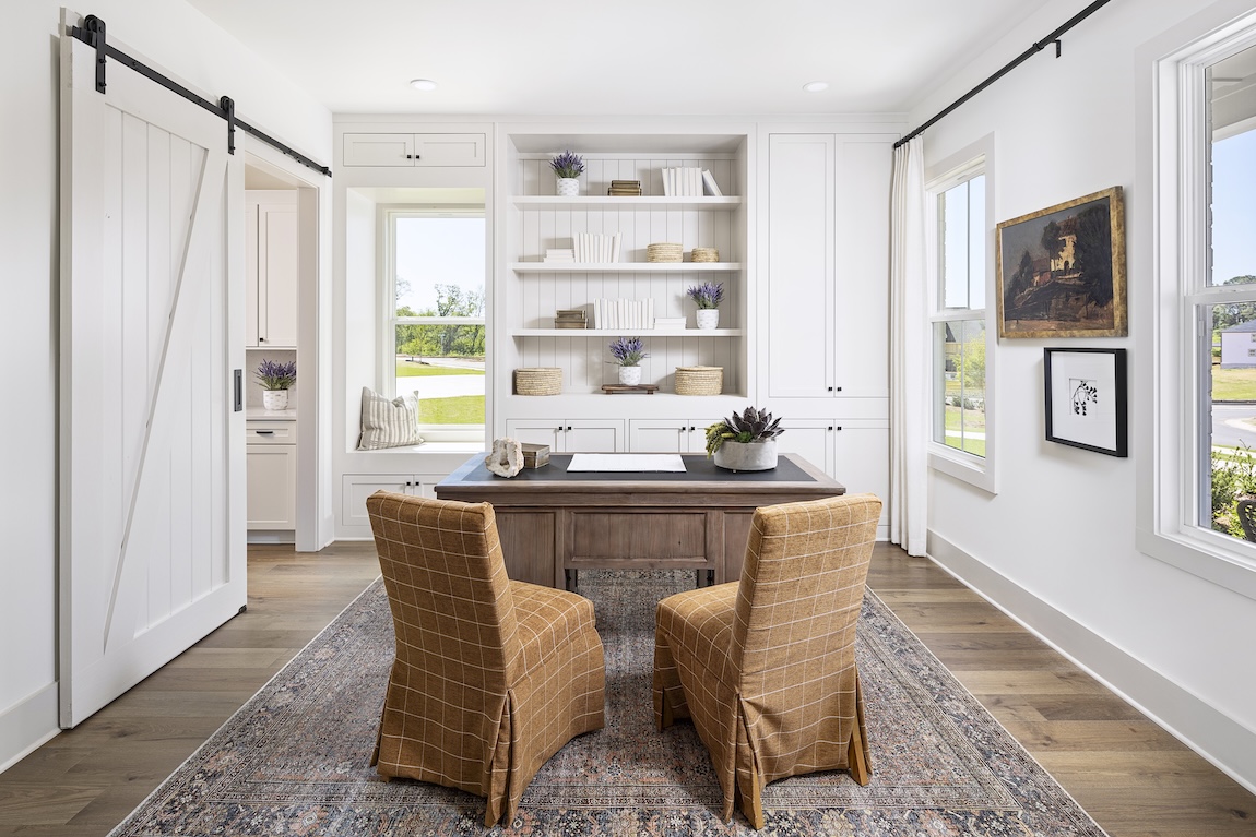 Luxury home office featuring barn doors, wooden floors, and reading nook. 