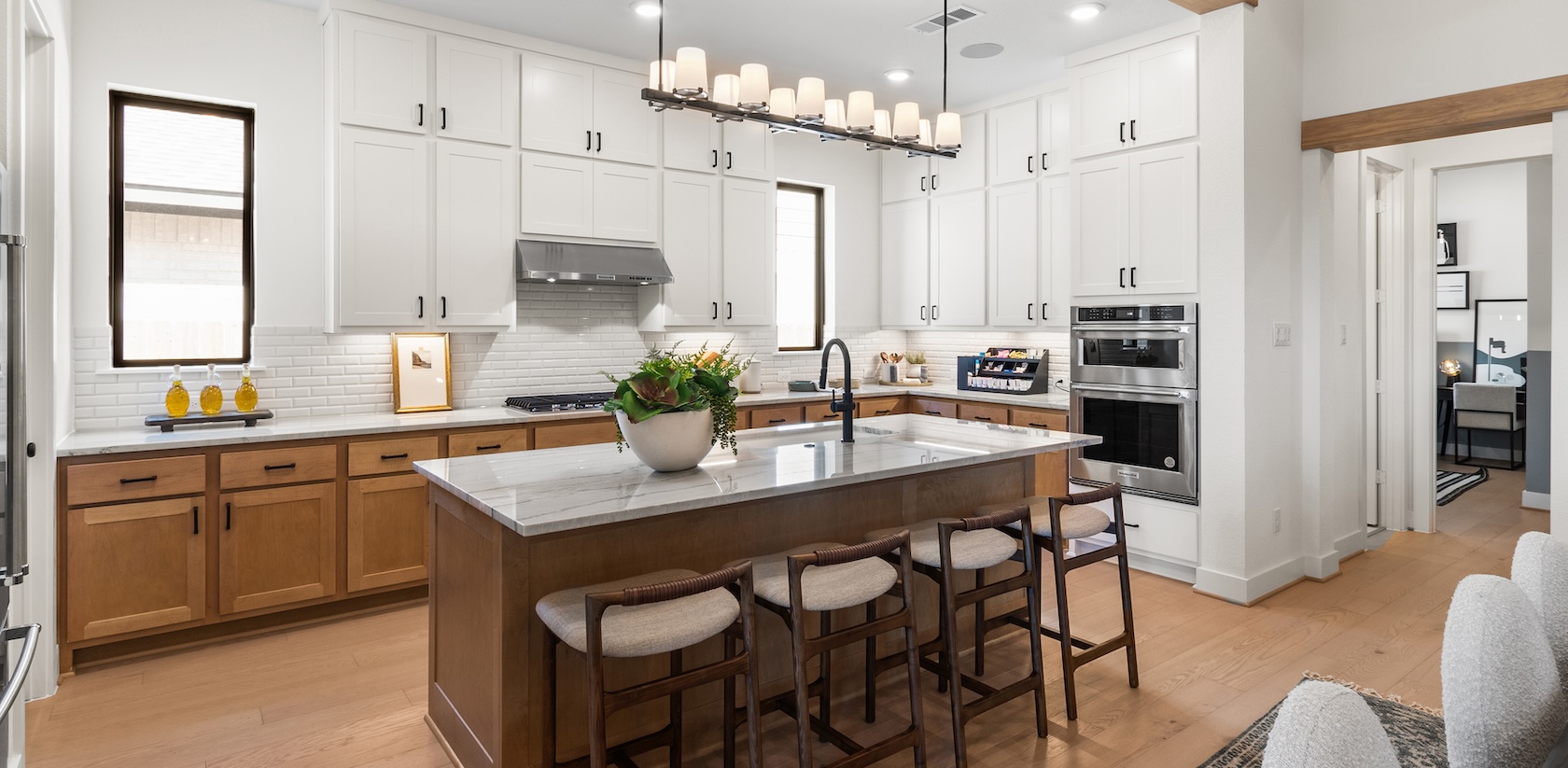 Luxury kitchen design with two-toned island featuring wooden accents and white quartz countertop.